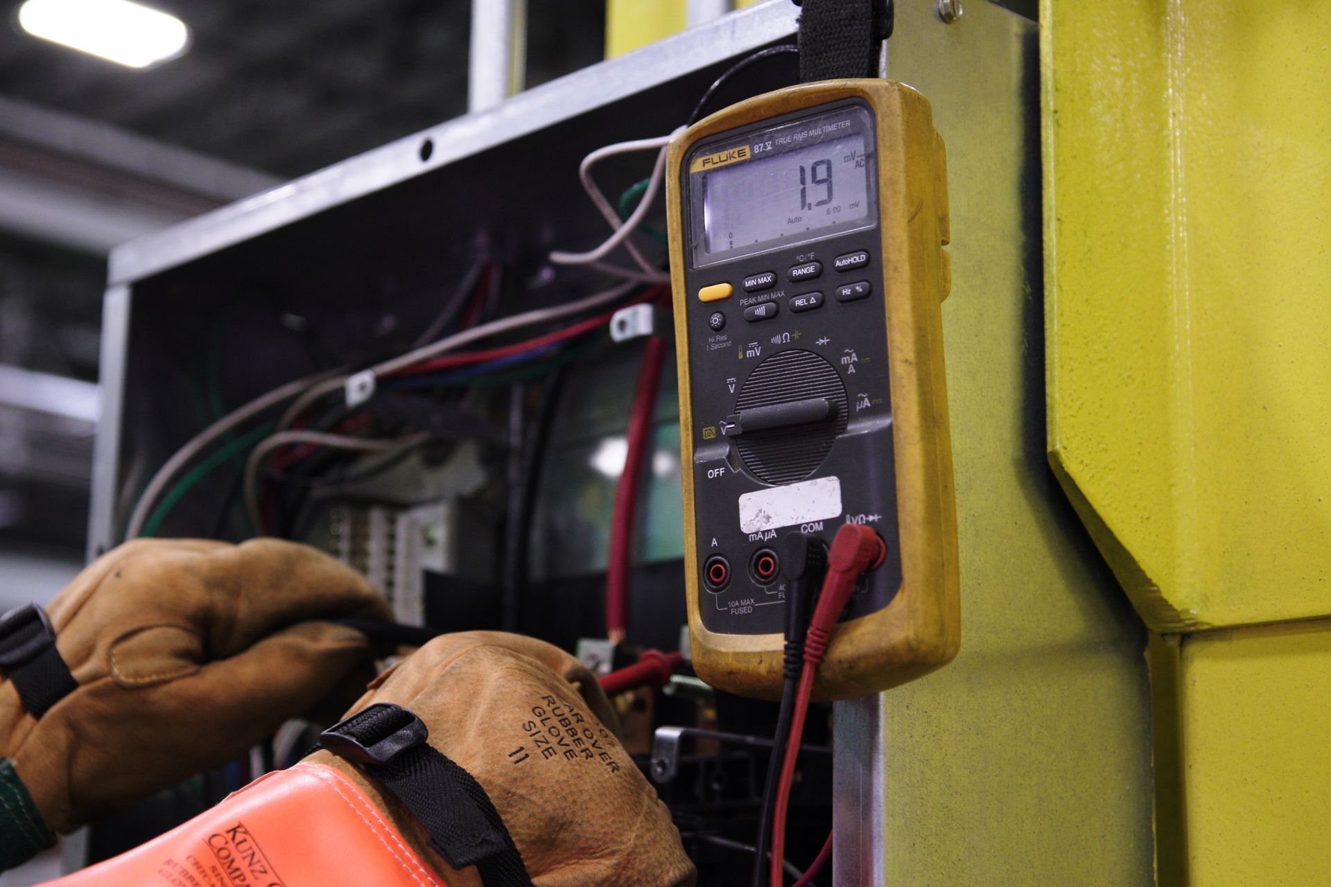 Arcwell Electric technician diagnosing a commercial switchboard with a digital multimeter